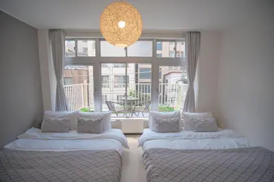 two beds in a room with a large window at 3 minutes to Shinjuku by subway-Nakanokaikan III in Tokyo