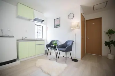 a living room with two chairs and a table and a clock at 3 minutes to Shinjuku by subway-Nakanokaikan III in Tokyo