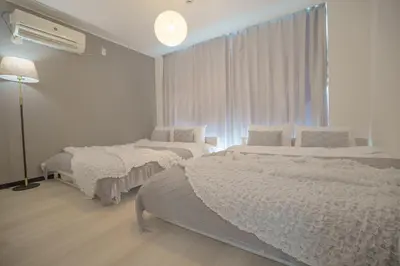 a white bedroom with two beds and a window at 3 minutes to Shinjuku by subway-Nakanokaikan III in Tokyo