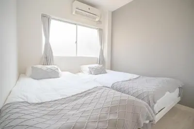 two beds in a white room with a window at 3 minutes to Shinjuku by subway-Nakanokaikan III in Tokyo