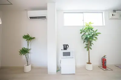 a room with two potted plants and a microwave at 3 minutes to Shinjuku by subway-Nakanokaikan III in Tokyo