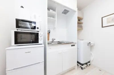 a white kitchen with a microwave and a refrigerator at \u30e1\u30eb\u30c7\u30a3\u30a2\u6771\u5800\u5207 in Tokyo
