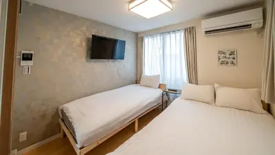 two beds in a room with a tv on the wall at \u3055\u304f\u3089\u65c5\u9928\u9ad8\u5186\u5bfa\u5317\u5343\u5229\u4f11101\u53f7\u5ba4 in Tokyo