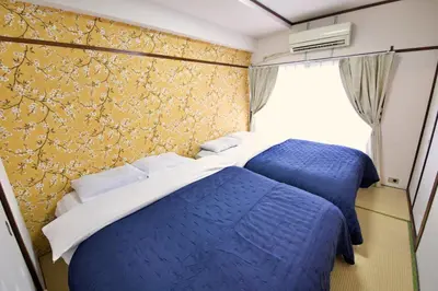 two beds in a bedroom with blue sheets and a yellow wall at \u9daf\u8c37 \u5bdb\u6c38\u5bfa\u5742\u30cf\u30a4\u30e0902 in Tokyo
