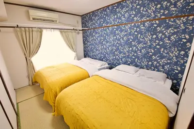 two beds in a small room with yellow sheets at \u9daf\u8c37 \u5bdb\u6c38\u5bfa\u5742\u30cf\u30a4\u30e0902 in Tokyo