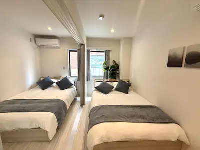 two beds in a room with white walls at SKY inn 1F in Tokyo