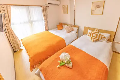 a bedroom with two beds with orange and white sheets at Nishiikebukuro 3people, mansion,2 mins to subway in Tokyo