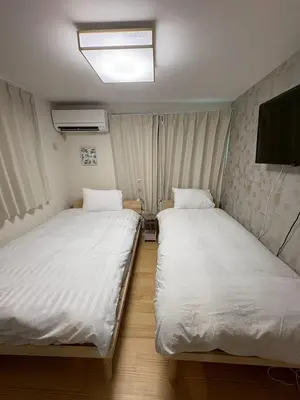 two beds in a room with white sheets at \u3055\u304f\u3089\u65c5\u9928\u9ad8\u5186\u5bfa\u5317\u5343\u5229\u4f11102\u53f7\u5ba4 in Tokyo