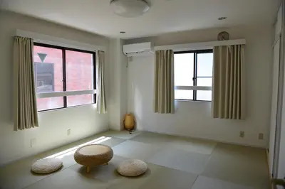 a living room with two windows and two ottomans at SKY inn 2-3F in Tokyo