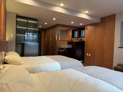 a bedroom with two beds and a kitchen with a refrigerator at A3 Shinjuku Business District hotel, 9 mins to ST Max 4P \u65b0\u5bbf\u5546\u52a1\u533a \u5168\u65b0\u88c5\u4fee \u4ea4\u901a\u4e2d\u5fc3 \u8f66\u7ad99\u5206\u949f \u6700\u59274\u4eba \u76f4\u8fbe\u65b0\u5bbf \u6d89\u8c37 \u8868\u53c2\u9053 \u54c1\u5ddd \u6c60\u888b \u4e0a\u91ce \u4ee3\u4ee3\u6728 \u94f6\u5ea7 \u539f\u5bbf in Tokyo