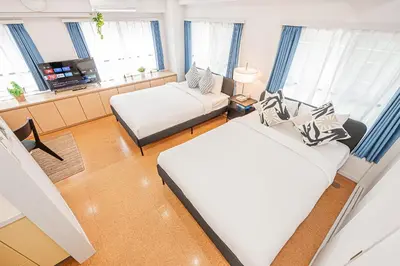a bedroom with two beds and a room with windows at phoneix apt ginza in Tokyo