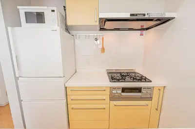 a small kitchen with a white refrigerator and a stove at phoneix apt ginza in Tokyo