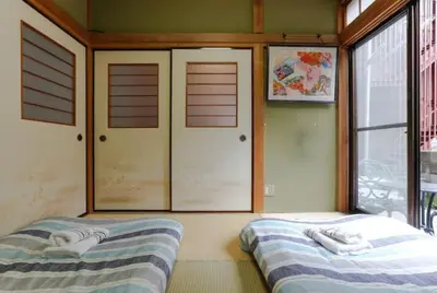 two beds in a room with doors and windows at \u897f\u65b0\u5bbf\u548c\u5eb5 wa-an homestay in Tokyo