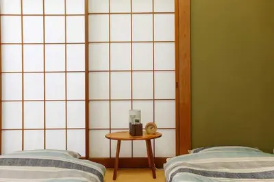a room with two beds and a table with a alarm clock at \u897f\u65b0\u5bbf\u548c\u5eb5 wa-an homestay in Tokyo