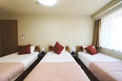 a room with three beds with red pillows at \u96fb\u8eca\u3067\u65b0\u5bbf\u307e\u306710\u52063ldk2\u500b\u30c8\u30a4\u30ec2\u500b\u30b7\u30e3\u30ef\u30fc\u5ba4\u7121\u6599\u99d0\u8eca\u5834\u5ead\u4ed8\u304d in Tokyo