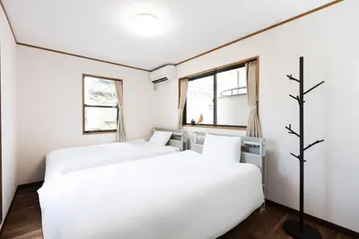 two beds in a room with white walls and windows at Kotori Ikebukuro in Tokyo