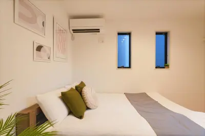 a white bedroom with a bed and three windows at Tomo House Yotsuya-Sanchome 101 - from 6 minutes station \u56db\u8c37\u4e09\u4e01\u76ee 101 \u99c5\u304b\u3089\u5f92\u6b696\u5206 in Tokyo