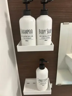 three bottles of shampoo and body soap on shelves in a bathroom at Fuji Hotel Tokyo Takadanobaba2 in Tokyo