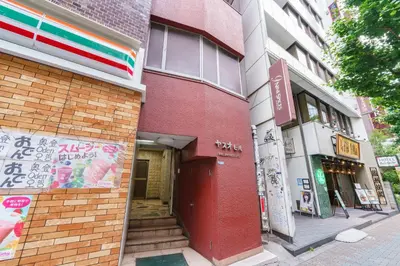 a red building with a red door on a street at feel Shinjuku STAY in Tokyo