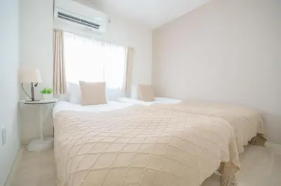 a white bedroom with two beds and a window at 3 minutes to Shinjuku by subway-Nakanokaikan II in Tokyo