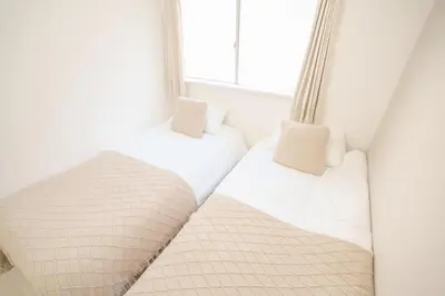 two beds in a room with a window at 3 minutes to Shinjuku by subway-Nakanokaikan II in Tokyo