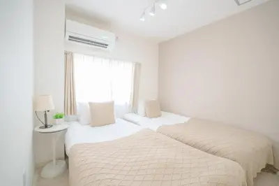 two beds in a white bedroom with a window at 3 minutes to Shinjuku by subway-Nakanokaikan II in Tokyo