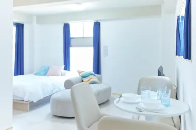 a white room with a bed and a table and chairs at Liberty Place Nakano by Tranova in Tokyo