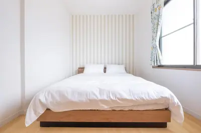 a bedroom with a bed with white sheets and a window at Witch's House Walk to Ikebukuro Tokyo's Ghibli Fairy Tale House in Tokyo