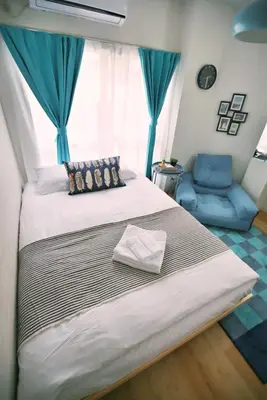 a bedroom with a large bed and a blue chair at BRT103 Ikebukuro Station Double Apartment in a Busy Business District, Yamanote Line and 8 Subway Lines Direct to Shinjuku, Shibuya, Ginza, Akihabara, Fully Equipped in Tokyo