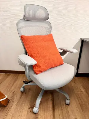 an office chair with an orange pillow on it at torico takinogawa in Tokyo