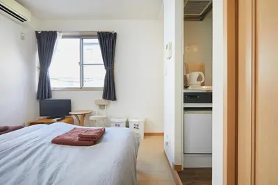 a bedroom with a bed and a kitchen with a window at 202 Nishi-Shinjuku Gochome Station 5 minutes on foot in Tokyo