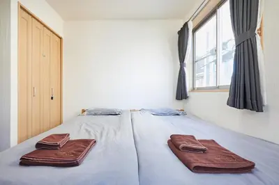 a bed with two brown towels on it with a window at 202 Nishi-Shinjuku Gochome Station 5 minutes on foot in Tokyo