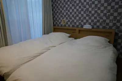 a bed with white sheets in a bedroom at 301 Nishi-Shinjuku-Gochome Station 5 minutes on foot in Tokyo