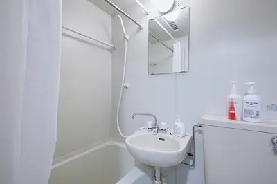 a white bathroom with a sink and a shower at 301 Nishi-Shinjuku-Gochome Station 5 minutes on foot in Tokyo