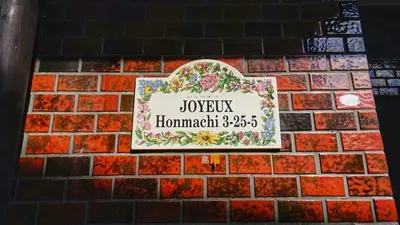 a sign on a brick wall with flowers on it at Shibuya Star 101 4 mins to Shinjuku Free WiFi in Tokyo