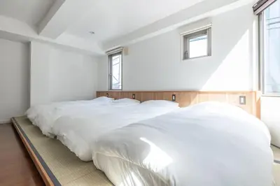 a bedroom with a large bed with white sheets at JR LINE Neko and Mado in Tokyo