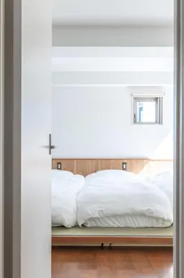 a bedroom with a bed with white sheets at JR LINE Neko and Mado in Tokyo