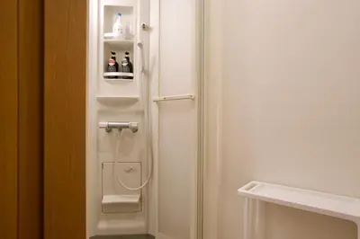 a bathroom with a white door with bottles on a shelf at Ueno Hoshi-5 minutes from Iriya Station-1 stop from Ueno station in Tokyo