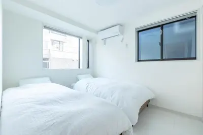 two beds in a white room with a window at JR Line yamanote ikebukuro in Tokyo