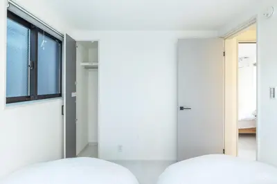 a bedroom with white walls and a window and two beds at JR Line yamanote ikebukuro in Tokyo