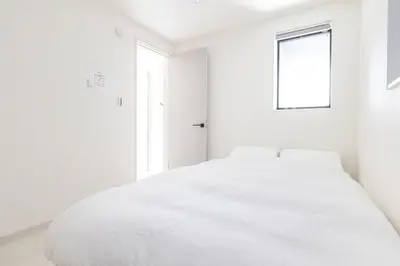 a white bedroom with a bed and a window at JR Line yamanote ikebukuro in Tokyo