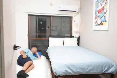 a man laying on top of two beds in a room at 2 beds near Higashinakano st. 5 min to Shinjuku in Tokyo
