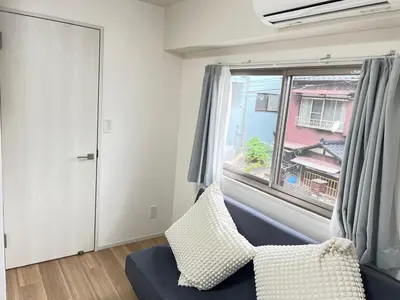 a living room with a blue couch and a window at Ikebukuro Area 2F5 NishiikeApartment in Tokyo