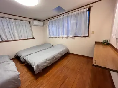 a bedroom with two beds and two windows at \u306b\u3058\u3044\u308d\u90b8\u6771\u4eac\u5927\u5cf6\u99c5\u524d in Tokyo