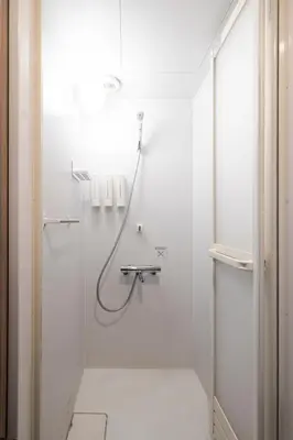 a white bathroom with a shower with a hose at Pagi Hotel in Tokyo