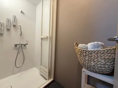 a bathroom with a shower with a basket next to a mirror at Pagi Hotel in Tokyo