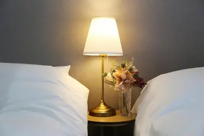 a lamp with a vase of flowers on a table between two beds at M206 Easy access to Ikebukuro, Ginza, Shinjuku in Tokyo