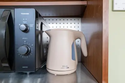 a white tea kettle sitting next to a microwave at 長期ステイ歓迎 ポップ ディズニー風 TDR スカイツリー好アクセス 定員3名 東京駅10分 駐車場予約 送迎有 HOTEL DREAM MUSIC Tōyōchō japanese-pop in Tokyo