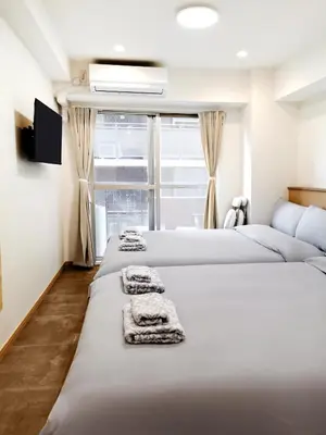 two beds in a room with towels on them at Fukuda House Shinjuku in Tokyo