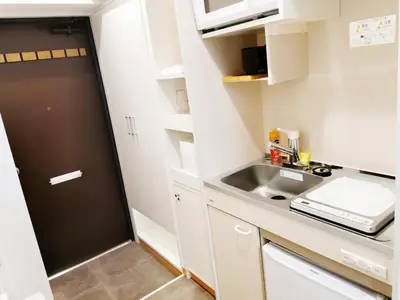 a small kitchen with white cabinets and a sink at Fukuda House Shinjuku in Tokyo